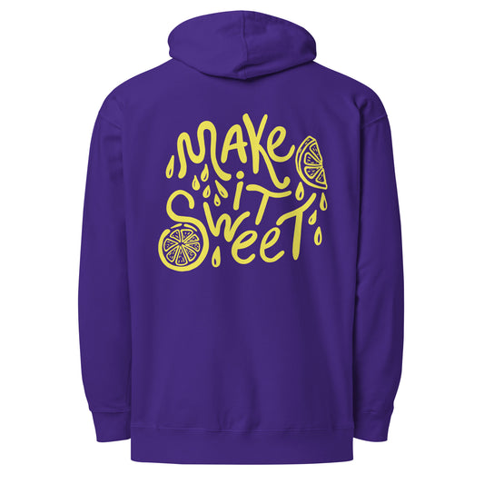 A purple pullover hoodie shown from the back, featuring a large yellow graphic print that reads 'MAKE IT SWEET' in a stylized font with lemon slice illustrations and droplet details.